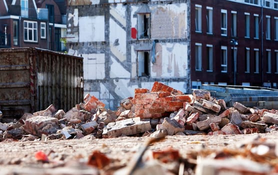 Demolition of a residential district in the Netherlands. There is some rubble around a builders skip.