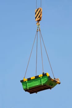 Green builders skip lifted by a crane
