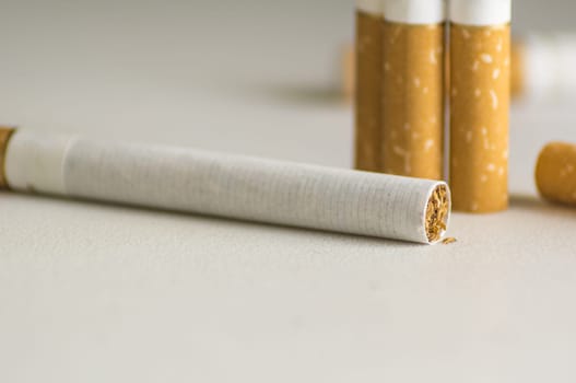 four cigarettes, three standing and one lying on a white plain