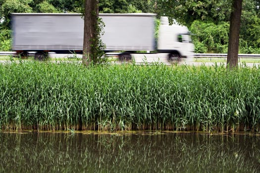 Nature and green next to the highway where a trucker is doing its job