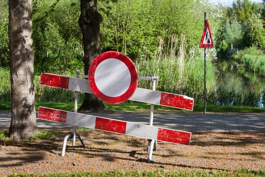 Construction barrier with a no entry sign. Men at work sign near the pavement in the background