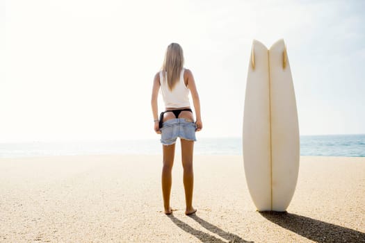 Beautiful young surfer girl getting ready to surf
