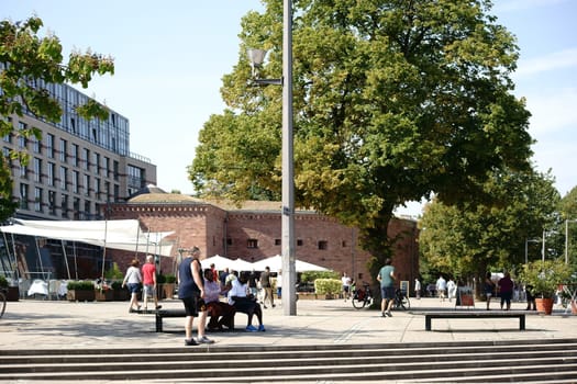 Mainz,Germany - August 22,2015: The Rheinufer Promenade on the terraces of Fort Malakoff with passers-by sitting on park benches under a tree on August 22,2015 in Mainz.
