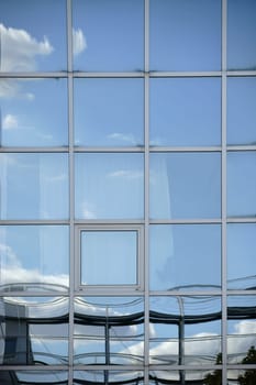 A white cloud and reflections in the windows of a modern facade.