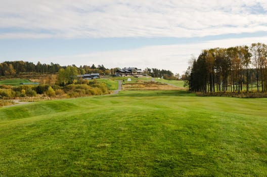 empty golfcourse at autumn and the clubhouse on the hill