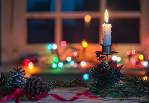 Candle with Christmas decoration, blurred light background
