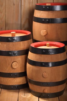 three old beer barrels with wooden plugs on a wooden background