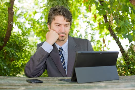worried businessman with digital tablet, outdoors