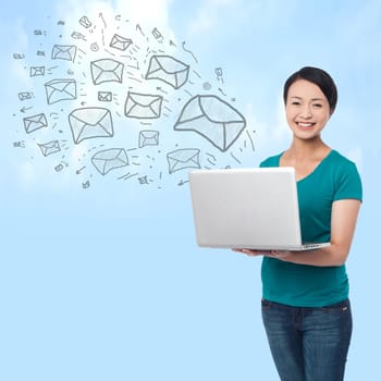 Pretty woman sending e-mails from a laptop, sky background
