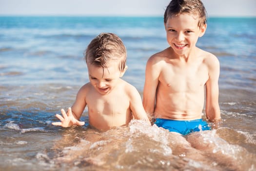 two smiling boys sitting on beach