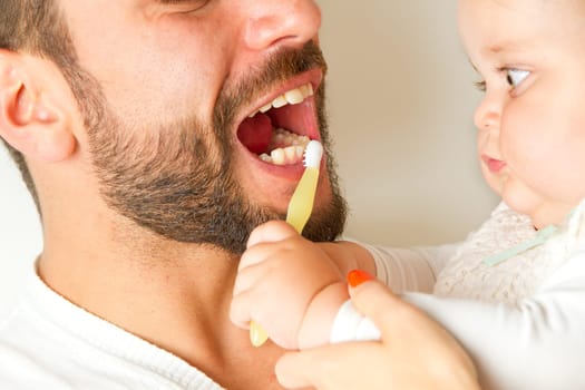 Baby brushes teeth from dad