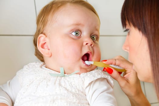 Mum brushes her baby's teeth