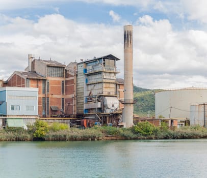 The old chemical factory with chimneys and silo on the banks of the river