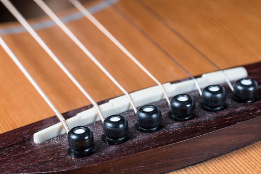 Guitar Saddle and Bridge close up on a steel string guitar.