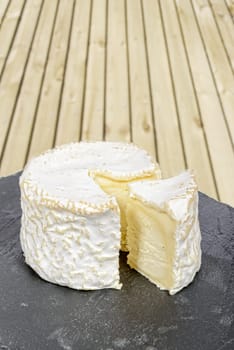 french cheese placed on a black slate, wood in background