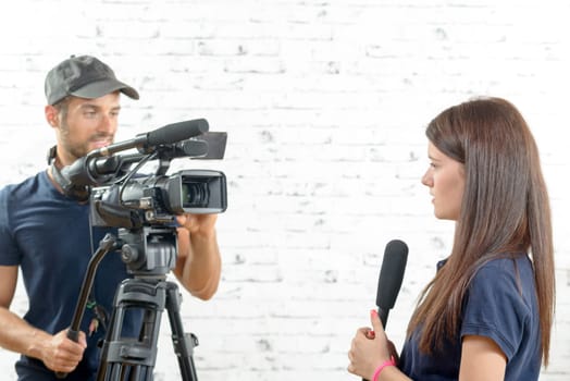 a young woman journalist with a microphone and a cameraman