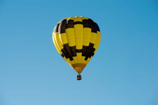 a black and yellow hot air balloon in a blue sky