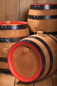 three old beer barrels with wooden plugs on a wooden background