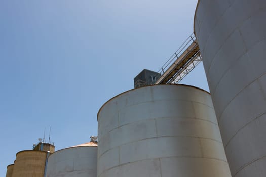 Large steel grain silos with cloudless blue skies.