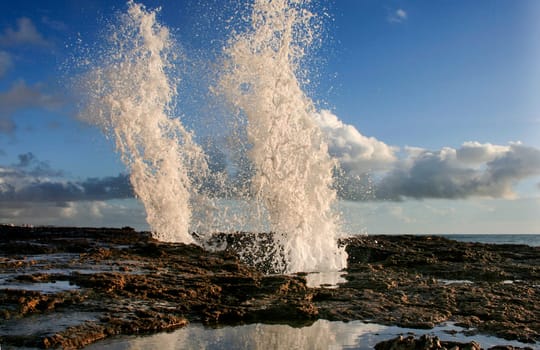 blow hole on Cadiz coastline sending two burst of water high into the air, Spain