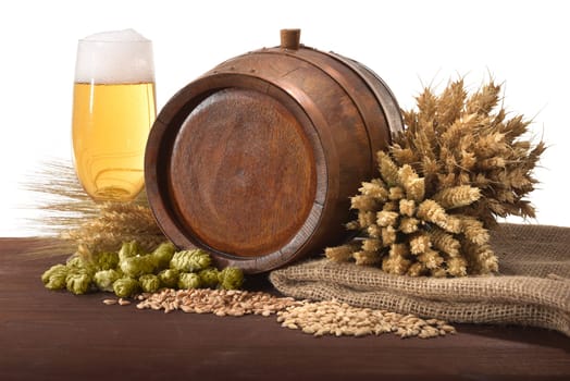 Old wooden barrel with beer glass,wheat,barley,hops and malt against a white background