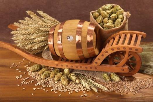 Old barrel with wheelbarrow,wheat,barley,hops and malt