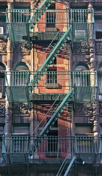 Colorful apartment buildings facades with emergency escapes. Typical New York City rental complexes with fire escape stairs next to the windows