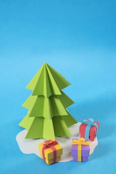 Christmas tree in paper cut handmade style with gift boxes on colorful blue background. Ideal for xmas greeting card, holiday poster or web.