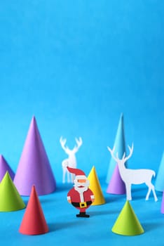 Christmas colorful paper craft scene with santa, deer silhouettes and xmas pine tree shapes, includes copy space. Ideal for holiday greeting card, poster or web.