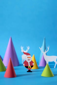Christmas scene with handmade paper cut santa, deers and pine tree shapes, includes copy space. Ideal for holiday greeting card, poster or web.