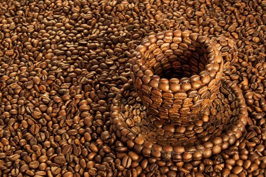 Close up view of a cup covered with coffee beans above a floor covered with coffee beans