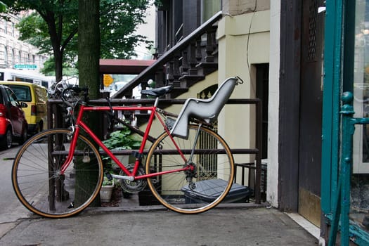 Red Bike with baby chair parked on one sidewalks of New York City