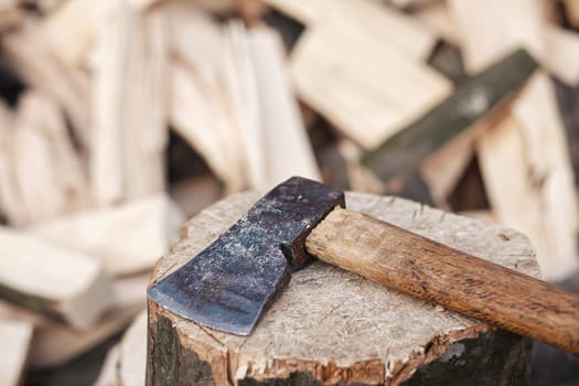 Axe lies on a stump on a background of chopped firewood