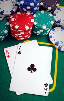 Stack of chips and two aces on the table on the green baize - poker game concept