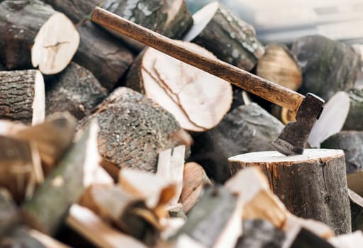 Axe stuck in a stump on a background of chopped firewood