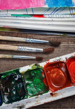Paints and brushes on a wooden background closeup