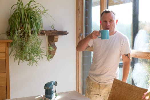 Wood joiner having a break from work and enjoying a cup of tea in the sunshine