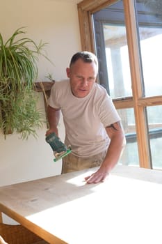 Wood joiner using an electric sander to smoothen a table surface