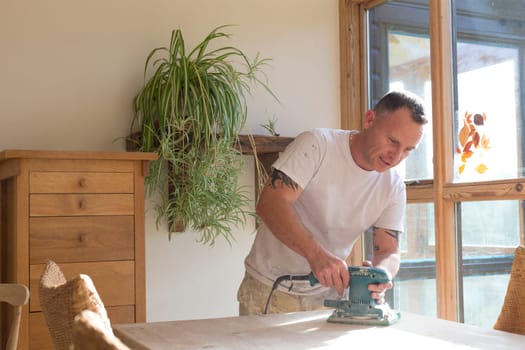 Wood joiner using an electric sander to smoothen a table surface