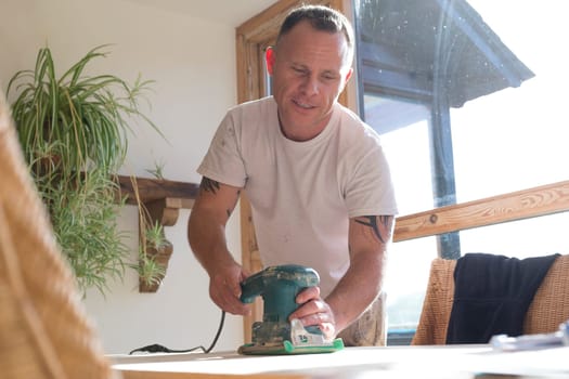 Wood joiner using an electric sander to smoothen a table surface