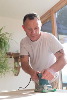 Wood joiner using an electric sander to smoothen a table surface