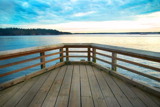 Wooden bridge on the sea coast with sunset and clouds