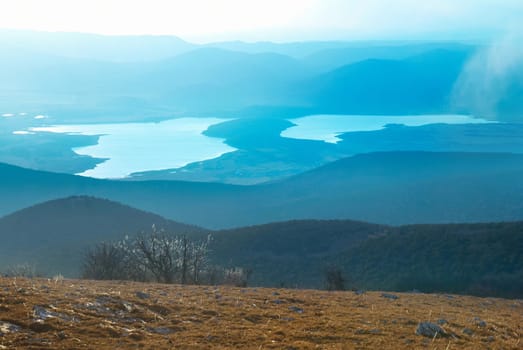 Sunset above the lake. Landscape with hills, clouds and sky.