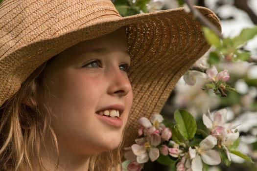 Girl with hat in front of flowering apple tree