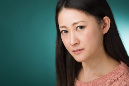 A headshot of a Japanese woman in hear early 30s on a simple green background.