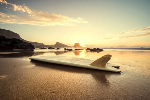 Silhouette of a surfboard at the beach with reflection