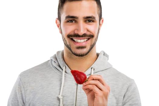 Happy young man eating a strawberry, isolated on white background