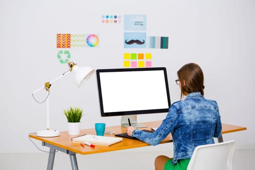 Woman working at desk In a creative office, using a computer