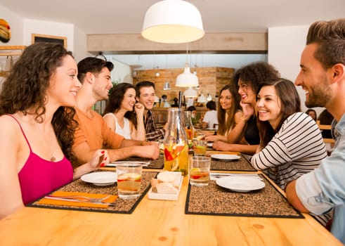 Multi-Ethnic Group of happy friends lunching and tasting the dessert at the restaurant