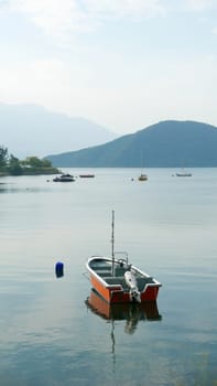 Red fishing boat on peaceful lake in day time